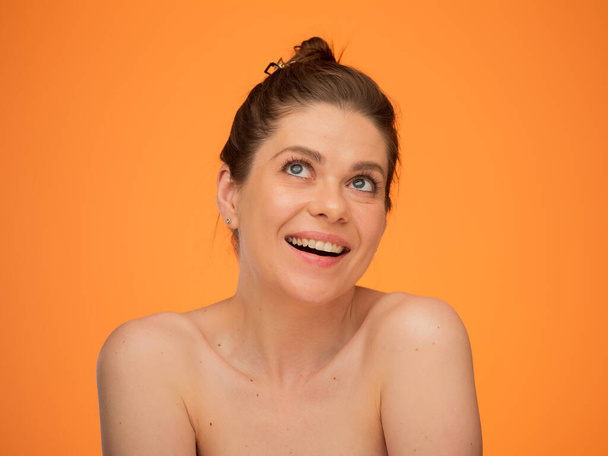 Happy dreaming woman looking up, isolated portrait on orange back with happy girl bare shoulders and bunch hair dress. Female emotional face. - Foto, immagini
