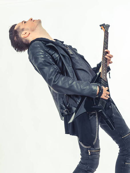 Жорсткий рок-гітарист насолоджується під час гри на електрогітарі на білому фоні
.  - Фото, зображення