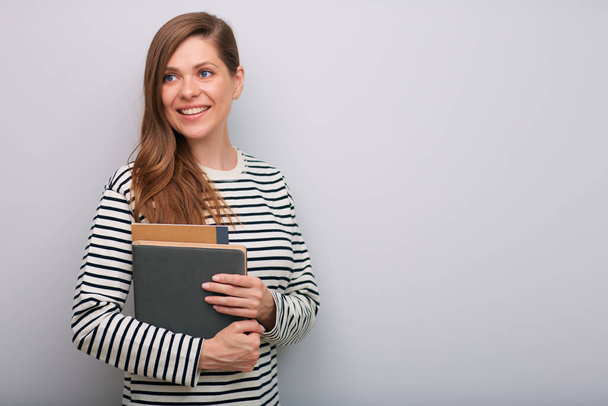 Smiling woman looking back over shoulder isolated portrait. Female student with book. - Photo, image