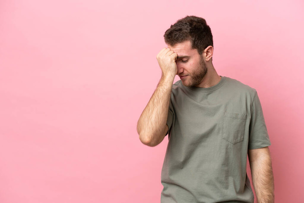 Young caucasian man isolated on pink background with headache - Zdjęcie, obraz