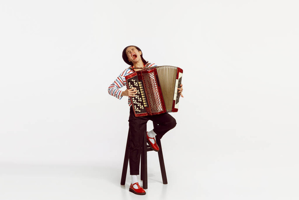 Portrait of talented beautiful woman playing accordion and expressively singing isolated over white studio background. Concept of live music, performance, retro style, creativity, artistic lifestyle - Fotografie, Obrázek