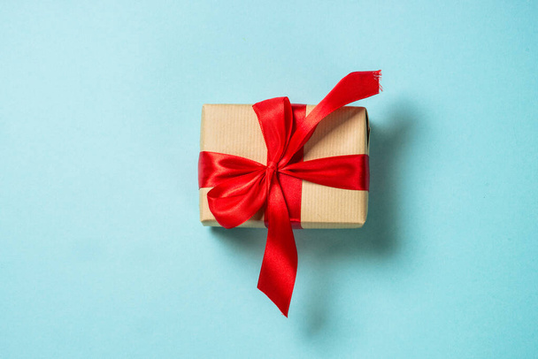 Christmas present box with red ribbon and glitter. Flat lay image on blue. - Fotoğraf, Görsel