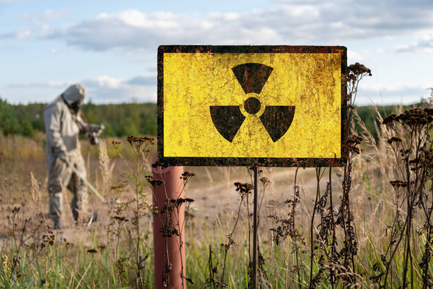 Old textural Sign of radiation hazard against the background of infected nature and forest. Concept: restricted area for visiting, increased background radiation. - Photo, Image