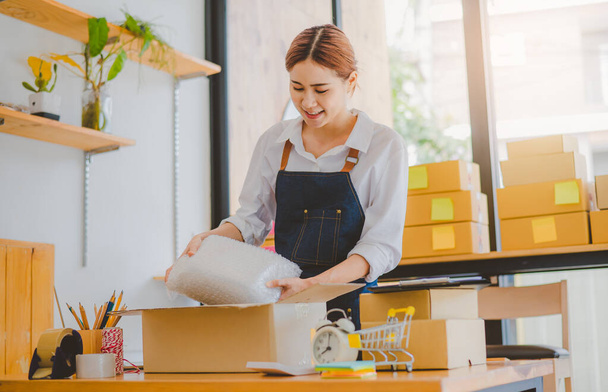 Online small business owners are packing their ordered products into the boxes for their customers based on the concept of online shopping - online shopping. - Foto, Imagen