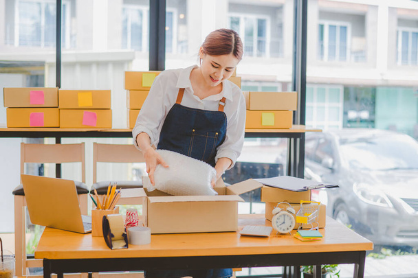 Online small business owners are packing their ordered products into the boxes for their customers based on the concept of online shopping - online shopping. - Foto, Imagen