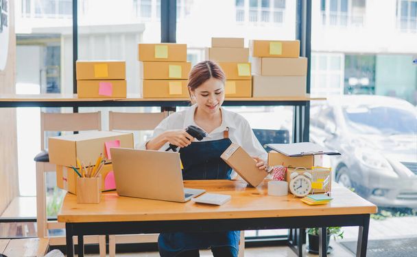 Small business owners online are scanning barcode-labelled parcel boxes with a barcode scanner to verify their product orders. of online retailers - online shopping - 写真・画像