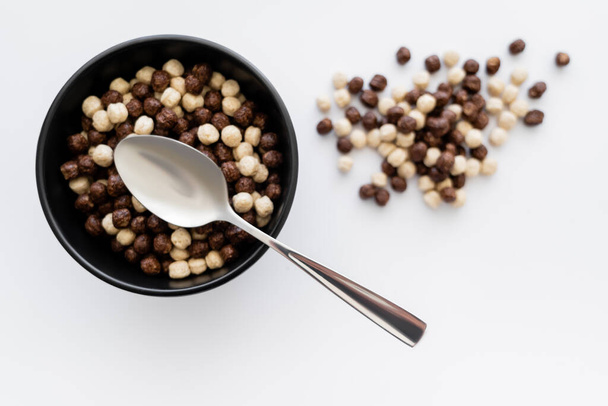 vista superior de bolas de cereais com sabores de chocolate e baunilha em tigela com colher isolada em branco  - Foto, Imagem