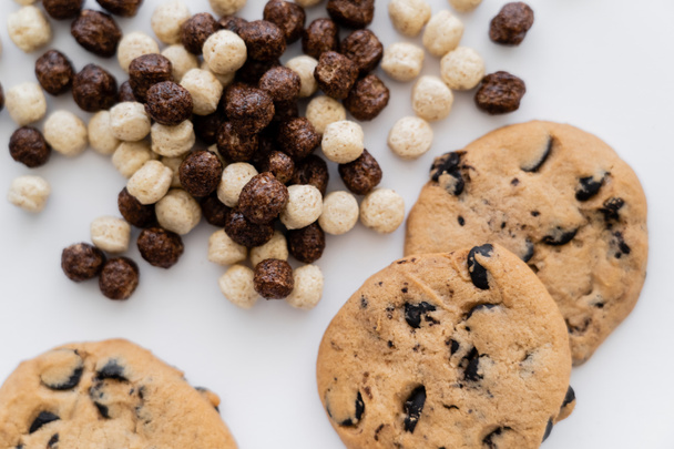 vista superior de bolas de cereais perto de biscoitos de chocolate chip isolado no branco  - Foto, Imagem