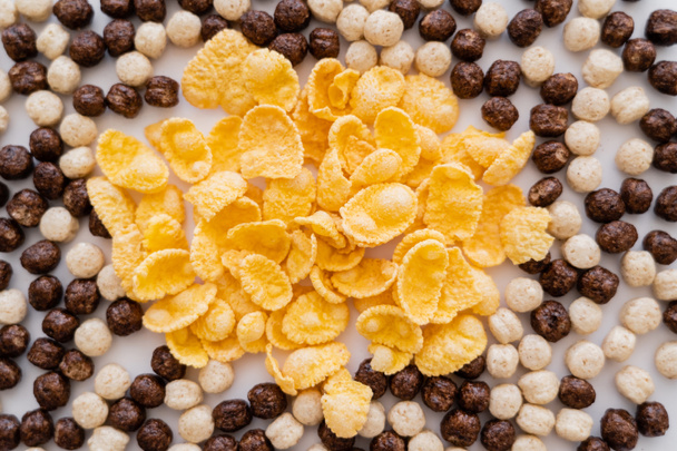 vista superior de copos de maíz y bolas de cereales con sabores de vainilla y chocolate en blanco - Foto, imagen