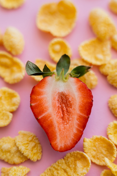 close up view of fresh strawberry around crispy corn flakes isolated on pink - Zdjęcie, obraz