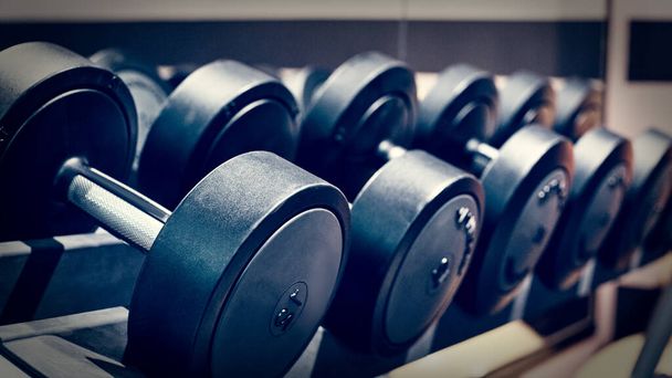 Closeup of modern gym interior with dumbbell equipment for weightlifting, image with vintage toning - Fotoğraf, Görsel