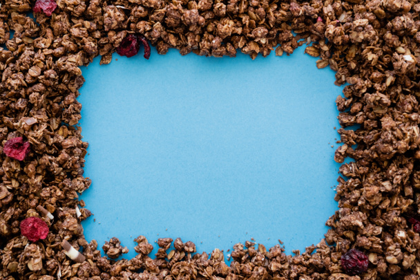 top view of frame made of crunchy and sweet oat granola isolated on blue  - Zdjęcie, obraz