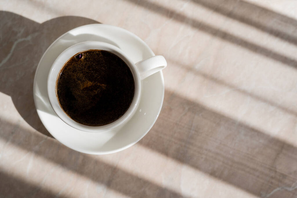 Draufsicht auf Tasse schwarzen Kaffee und weiße Untertasse auf Marmoroberfläche  - Foto, Bild