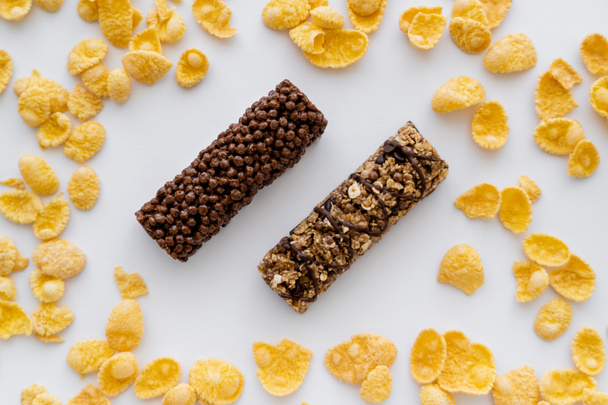 vrchní pohled na chutné granola tyčinky kolem křupavé kukuřičné vločky izolované na bílém  - Fotografie, Obrázek