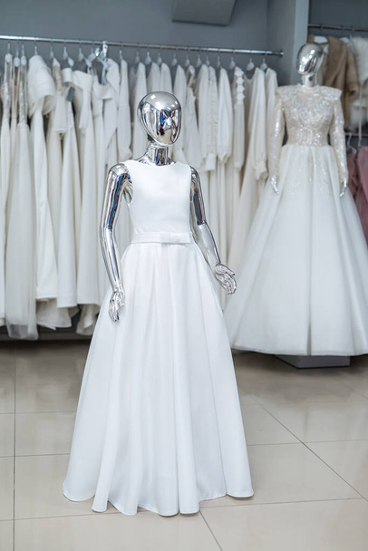 white wedding dresses on mannequin and away hanging on hangers in shop showroom  - Foto, Bild