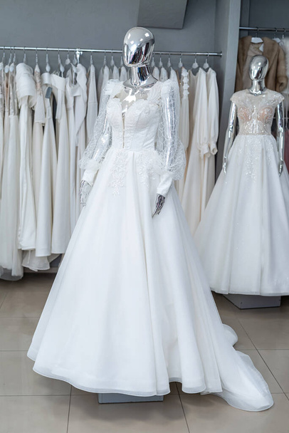 white wedding dresses on mannequin and away hanging on hangers in shop showroom  - Fotografie, Obrázek
