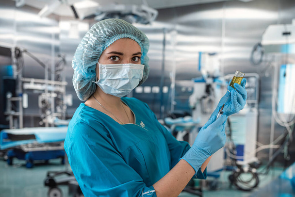 Atractiva doctora sosteniendo jeringa en quirófano para paciente. medicina. médicos de quirófano jeringa en las manos - Foto, Imagen