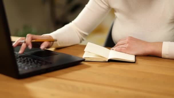 Mujer haciendo notas a mano en bloc de notas, mujer de negocios redactor freelancer trabajando en el ordenador portátil. Internet para el aprendizaje y búsqueda de empleo. - Imágenes, Vídeo