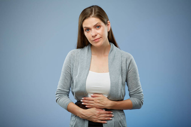 Woman with abdominal pain with hands on her stomach. isolated female portrait on blue. - Foto, Imagen