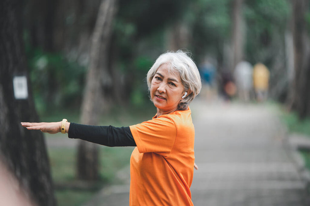 Oudere, witharige Aziatische vrouw die 's morgens vroeg in het park traint. - Foto, afbeelding
