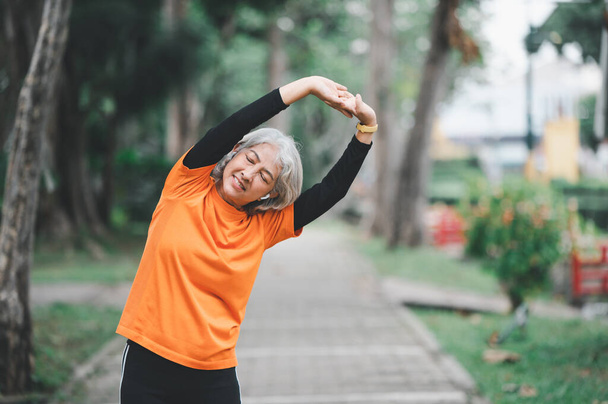 Elderly, white-haired Asian woman exercising in the park early in the morning. - Zdjęcie, obraz
