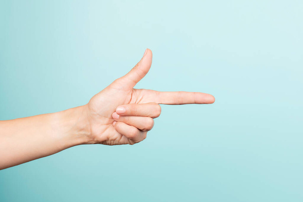 Woman hand gesture. Female hand points finger at something on light blue background. Front view - Φωτογραφία, εικόνα