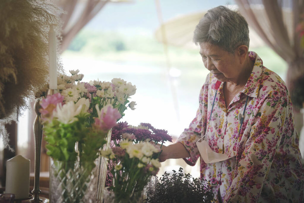 chryzantéma se starou ženou zdobí kytice ve skleněné váze na jídelním stole - Fotografie, Obrázek