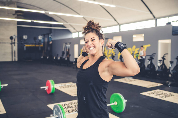 Ενεργός αθλητικός αθλητισμός γυναίκα δείχνει τους μυς της δικέφαλους υγιή τρόπο ζωής χαμογελώντας ευτυχισμένος - Φωτογραφία, εικόνα