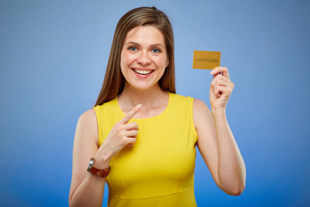 Smiling young lady in yellow dress with credit card pointing finger. isolated female portrait. - Zdjęcie, obraz