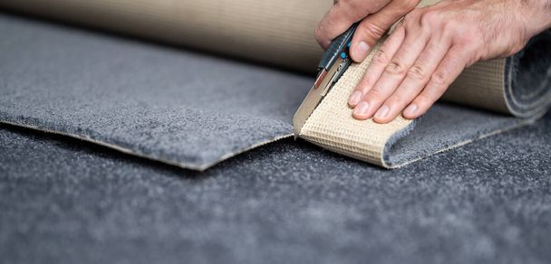 Handyman cutting a new carpet with a carpet cutter. - Photo, image