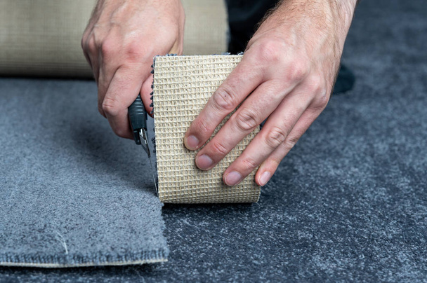Handyman cutting a new carpet with a carpet cutter. - Foto, immagini