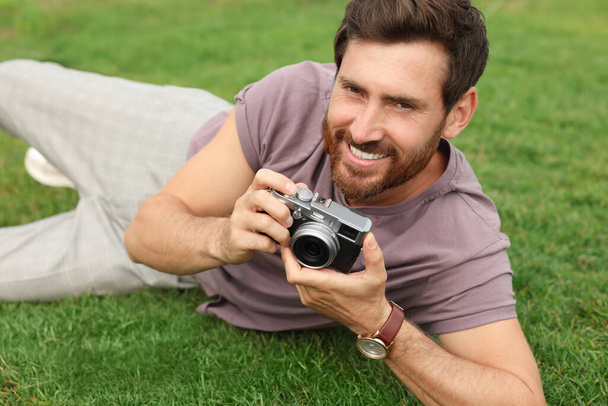 Egy férfi kamerával a zöld füvön. Érdekes hobbi. - Fotó, kép