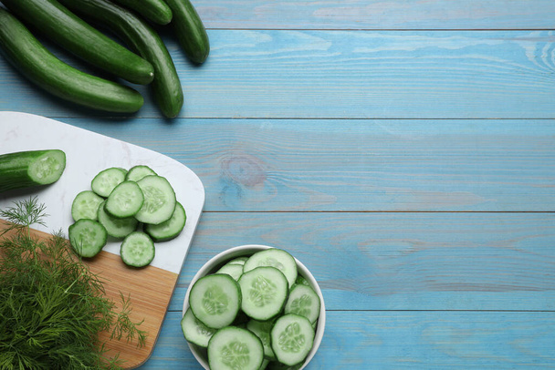 Fresh ripe cucumbers and dill on light blue wooden table, flat lay. Space for text - Valokuva, kuva