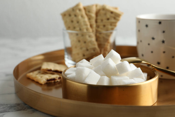 Refined sugar cubes in bowl and aromatic tea on white marble table, closeup - Foto, Imagem