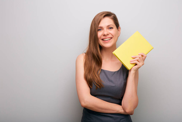 Smiling business woman in gray dress holding yellow book. isolated female business person portrait. - Zdjęcie, obraz