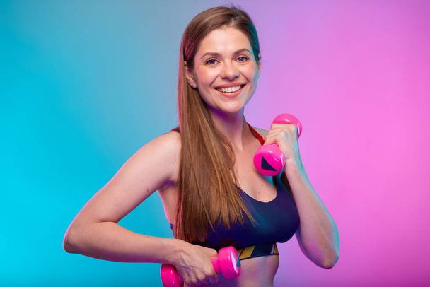 sporty woman in fitness sportswear doing exercise with dumbbells. Female fitness portrait isolated on neon multicolor background.  - Фото, зображення