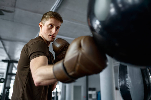 Fermer boxer boxe dans un sac de boxe avec un accent sélectif sur le visage concentré sérieux - Photo, image
