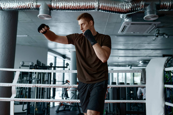Уверенный человек боксер делать спортивные тренировки бокс упражнения пробивая воздух в кольцо боковой вид замедленной съемки - Фото, изображение