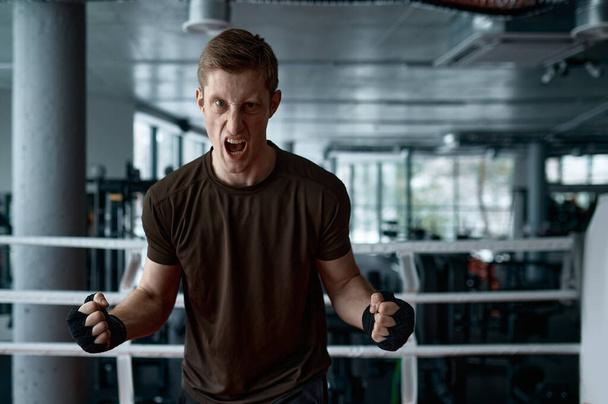 Portrait de boxeur agressif tenant les poings serrés prêt à la boxe dans l'anneau de sport - Photo, image
