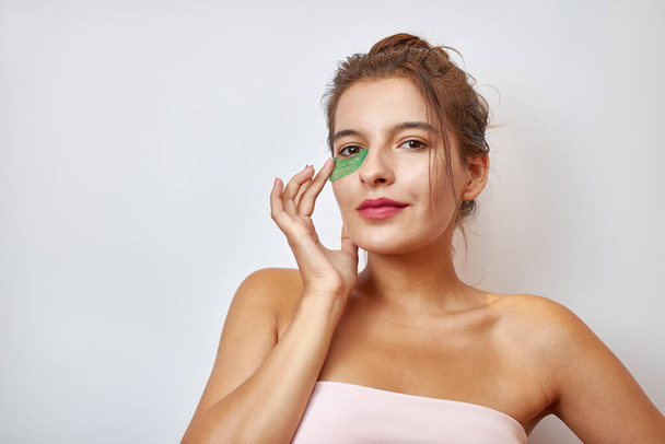 The girl uses collagen hydrogel patches under her eyes. Beauty concept, cosmetics for skin care around the eyes, lifting. Beauty salon. Wrinkle removal. - Φωτογραφία, εικόνα