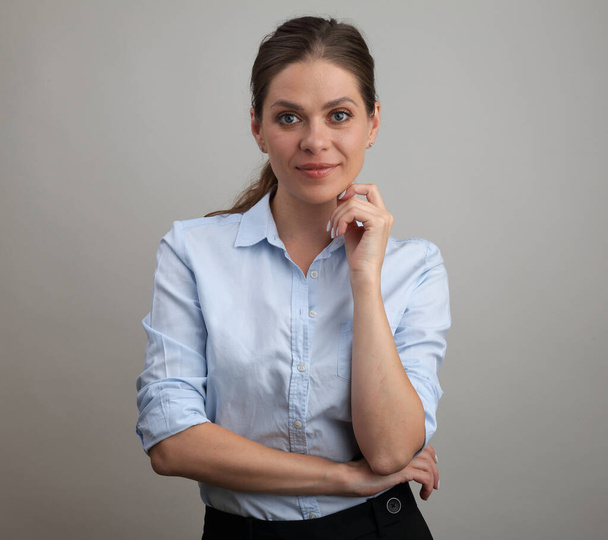Smiling woman in blue business shirt touches her chin. isolated woman portrait. - 写真・画像