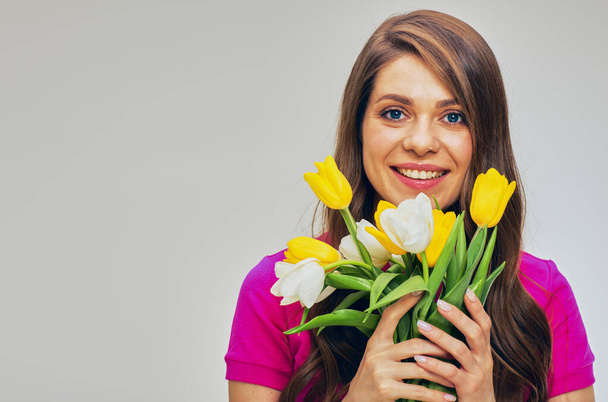 Young woman in red holding flowers bouquet in front of face. Isolated female studio portrait. - Photo, Image