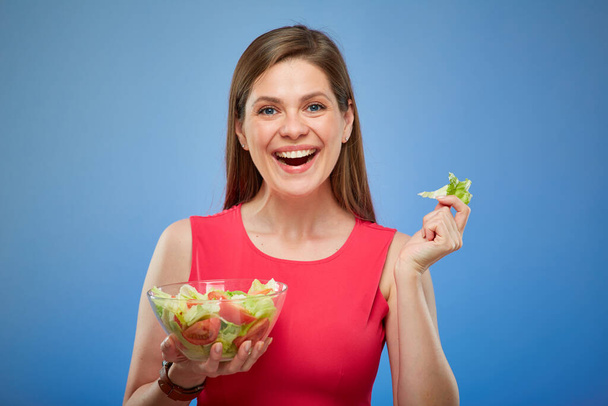 Young smiling lady in red eating green salad with hands. - Fotografie, Obrázek