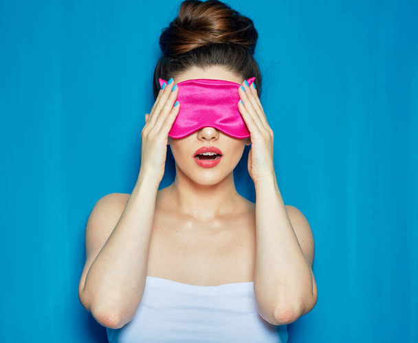 Surprising Woman in sleeping mask touching face. female person portrait isolated on blue wall back. - Foto, immagini