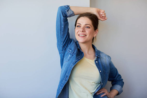 Happy smiling woman in blue denim shirt think and look away holding raised hand. - Photo, image