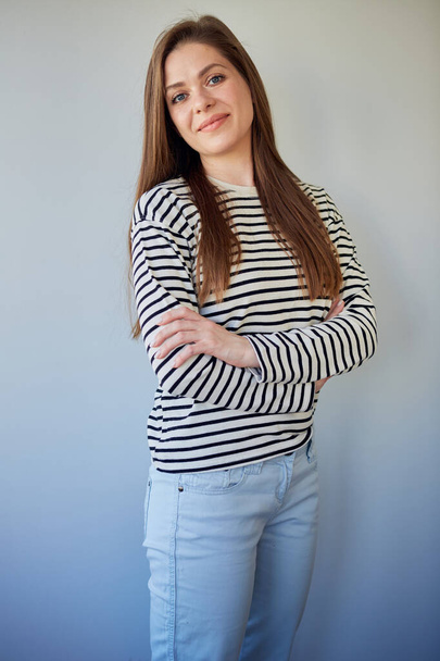 Smiling woman with long hair standing with crossed arms. Girl wearing jeans pants and striped shirt. - Foto, afbeelding
