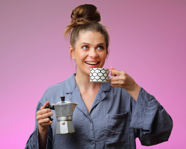 Smiling woman pajama dressed drinking coffee and holding geyser coffee maker, isolated on pink female face portrait - Fotografie, Obrázek