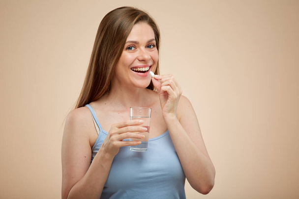 Smiling woman with drug pill and water glass, isolated female portrait. - 写真・画像