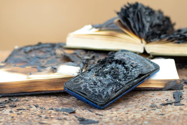 Обугленные книги и мобильный телефон после пожара - Фото, изображение