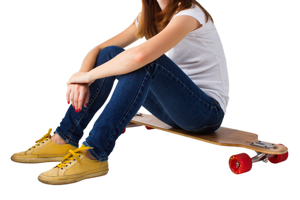 Young woman sitting on a skateboard - Фото, зображення